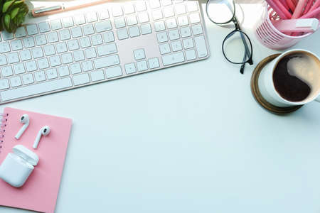 Woman workspace with coffee cup, pencil holder and notebook on white table.