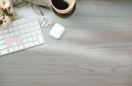 Top view cup of coffee, earphone, keyboard and glasses on wooden background.