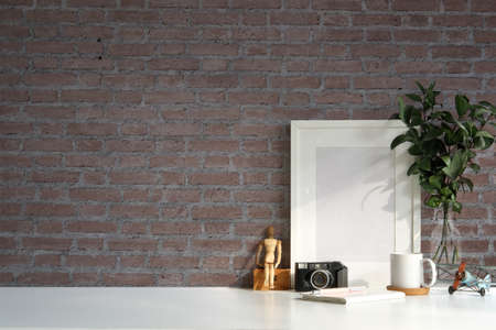 Photographer workspace with camera, picture frame, houseplant and coffee cup on white table with...