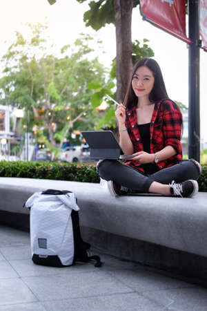 Beautiful young woman using laptop computer in city park.の写真素材