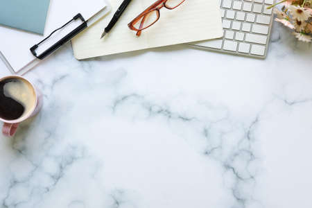 Top view stylish workspace with coffee cup, glasses, notebook and clipboard on marble table.の写真素材