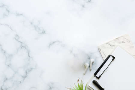 Top view wireless earphones, notebook and clipboard on marble table.の写真素材