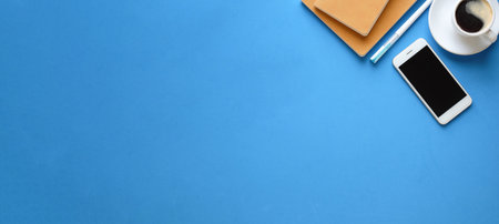 Top view mock up smart phone, coffee cup, and notebook on blue background. Copy space.の写真素材