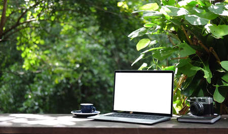 Laptop computer with white blank screen on wooden table in the garden.の写真素材