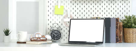 Front view computer laptop with empty display, books and potted plant on white table.の写真素材