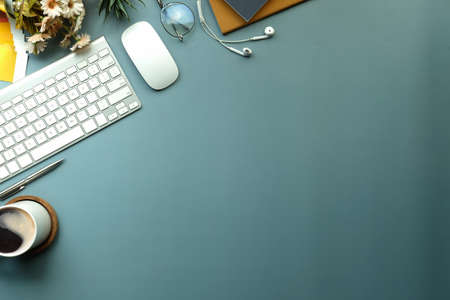 Creative workspace with coffee cup, books, earphone and keyboard.
