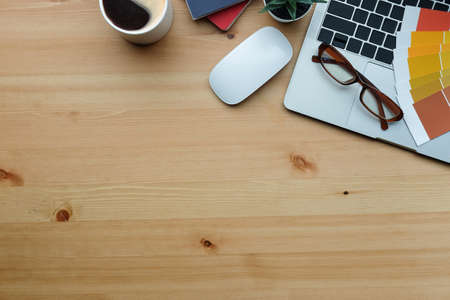 Graphic designer workspace with laptop computer, coffee cup and colour swatch.