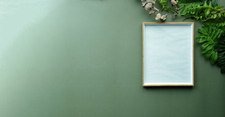 Empty picture frame and leafs on green background.の写真素材