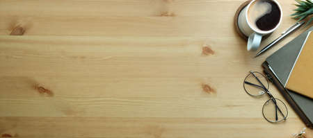 Top view notebooks, coffee cup and glasses on wooden table.の写真素材