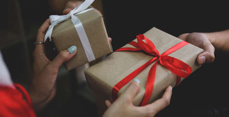 Close up view man giving Christmas present to wife and celebrating holidays at home.の写真素材
