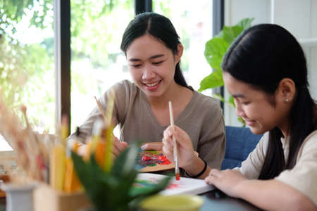 Happy young Asian mother and her daughter painting together at home.の写真素材