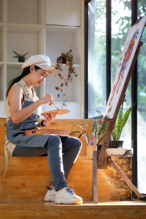 Portrait of asian woman painting picture on canvas with watercolour in her studio.の写真素材
