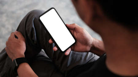 Close up view man using mobile phone in living room.