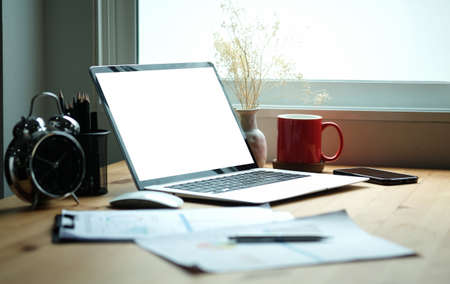 Computer laptop and coffee cup on wooden table. Blank screen for your advertising text.