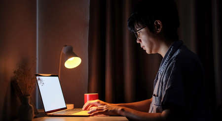 Asian man freelancer working with computer laptop at late night in bedroom.の写真素材