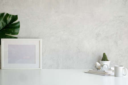 Empty picture frame, cactus, coffee cup and headphone on white table.の写真素材
