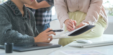Cropped shot businesswoman holding digital tablet and working with her colleague in office.の写真素材