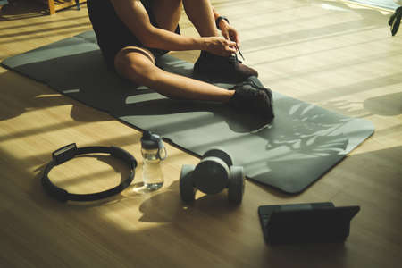 Young man tying shoelaces getting ready for exercise in living room.