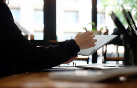 Close up view businesswoman holding stylus pen and writing on digital tablet.