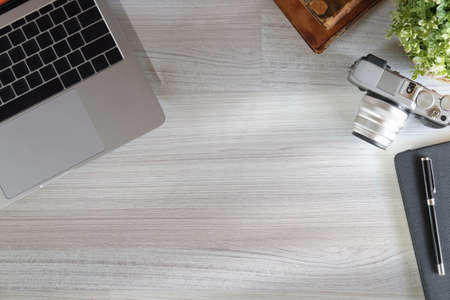 Top view laptop computer, camera, notebook and houseplant on wooden table.の写真素材