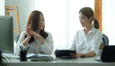 Two happy female employees working together at modern workplace.の写真素材