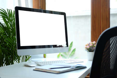 Comfortable workplace with modern computer on white table. Blank screen for your advertising text.