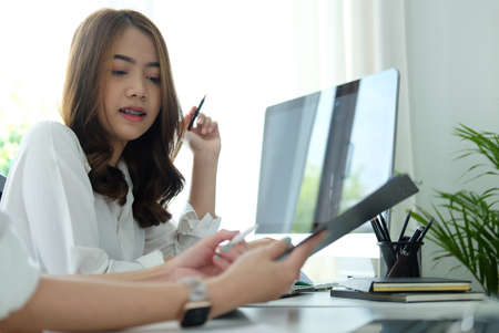Young business woman analysing financial document with her colleague at office desk.の写真素材