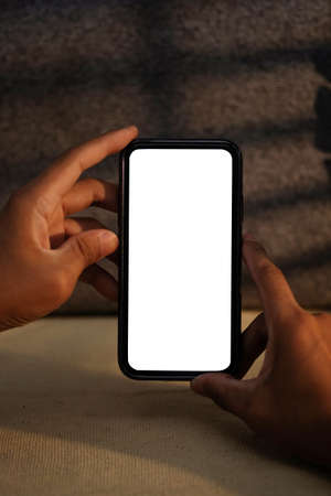 Man hands holding smartphone with white empty screen for advertisement text.
