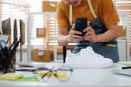 Cropped shot young man using smart phone taking a photo of product for upload to website.の写真素材