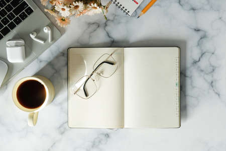 Woman workplace with laptop computer, coffee cup, notebook and glasses on marble background.の写真素材