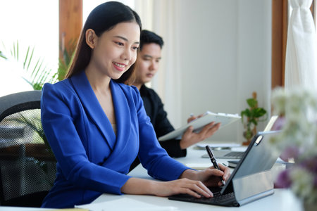 Attractive asian business woman using computer tablet while sitting in meeting room.の写真素材