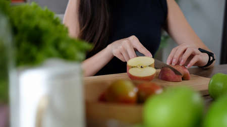 Cropped shot healthy woman cutting fruits on a wooden board while making healthy vegan food in kitchen.の写真素材