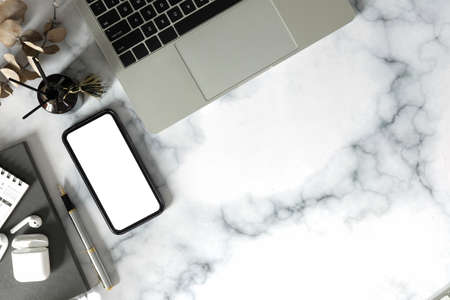 Top view feminine workplace with smart phone, laptop computer, wireless earphone and notebook on...