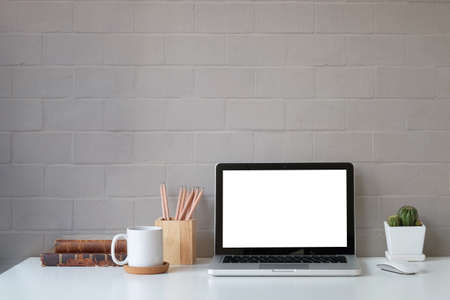 Front view computer laptop with blank screen, coffee cup, pencil holder and book on white table with...