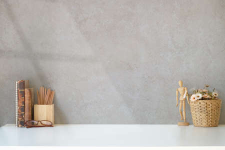 Stylish workplace with books, picture frame, houseplant and coffee cup on wooden table.
