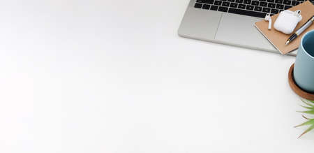White office desk with computer laptop, coffee cup, wireless earphone and notebook. Top view.の写真素材