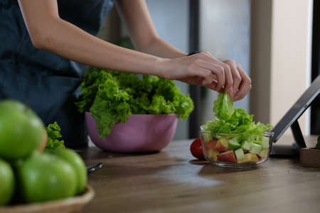 Young woman preparing vegetable salad in the kitchen. Healthy Lifestyle concept.の写真素材
