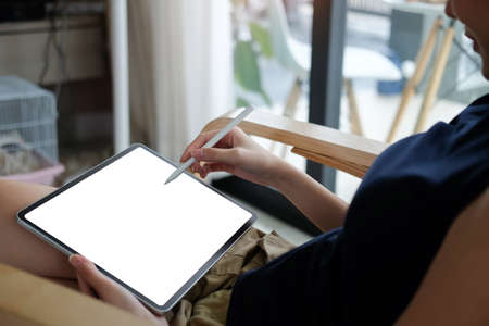 Casual young woman holding stylus pen writing on screen of digital tablet.の写真素材