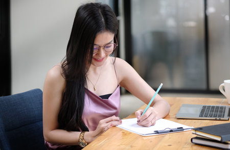 Focuses young female financial adviser checking financial report at office desk.の写真素材