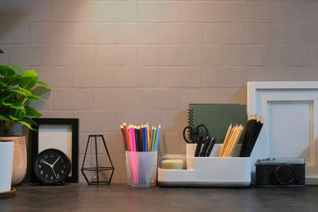 Stylish workplace with stationery, picture frame and houseplant on black table.の写真素材