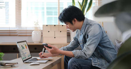 Side view millennial man searching information online, working with computer laptop in living room.の写真素材