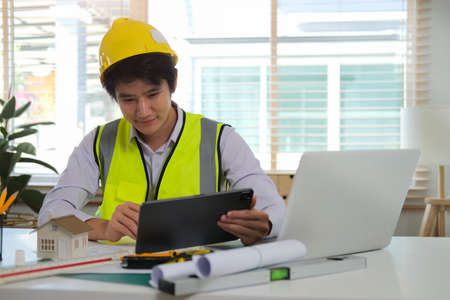 Engineer checking information on a digital tablet working on architectural project at office.の写真素材