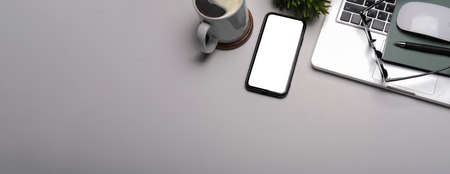 Modern workplace with smart phone, laptop computer, coffee cup, eyeglasses and notebook.の写真素材