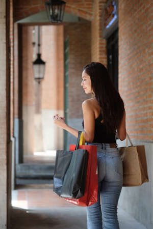 Portrait of beautiful asian woman holding shopping bags and walking on the city street.