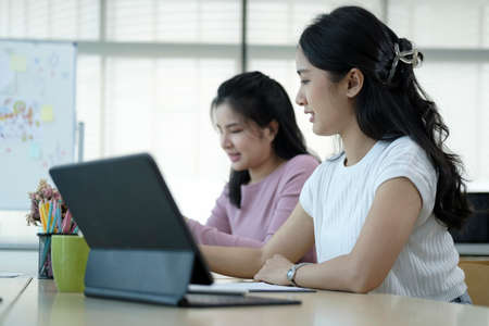 Two creative young women working on project together at modern workplace.の写真素材