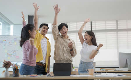 Overjoyed young business people celebrating success startup project together at office meeting.の写真素材