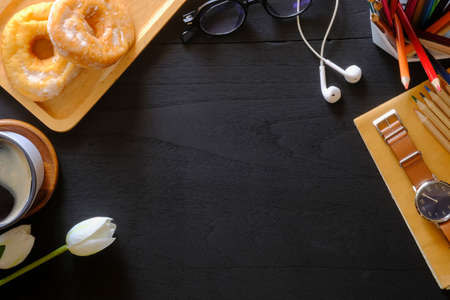 Stylish workplace with wristwatch, coffee cup, glasses and donuts on à¸´black wooden table. Top view, Copy space.の写真素材