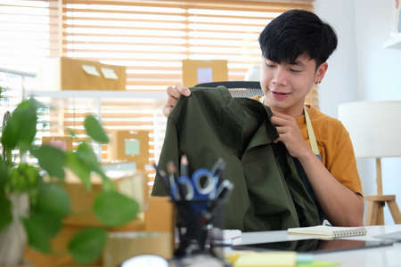 Asian male business owner working, packing new clothing for shipping to customer. Startup small...
