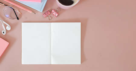 Empty notebook, coffee cup and earphone on pink background. Feminine workplace, Top view, Flat lay.