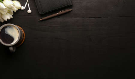 Luxury workplace with notebook, coffee cup and earphone on black wooden table. Top view.の写真素材